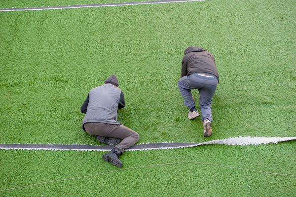 two men working on synthetic grass