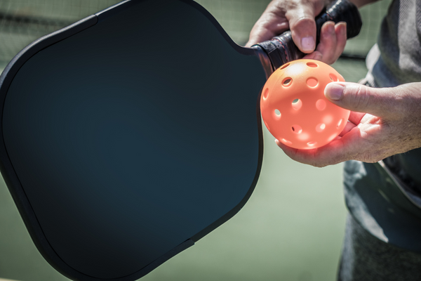pickleball paddle and ball in hand