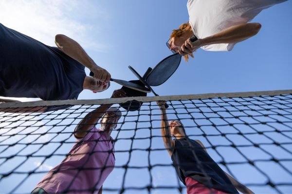 four-pickleball-players-clinking-their-paddles