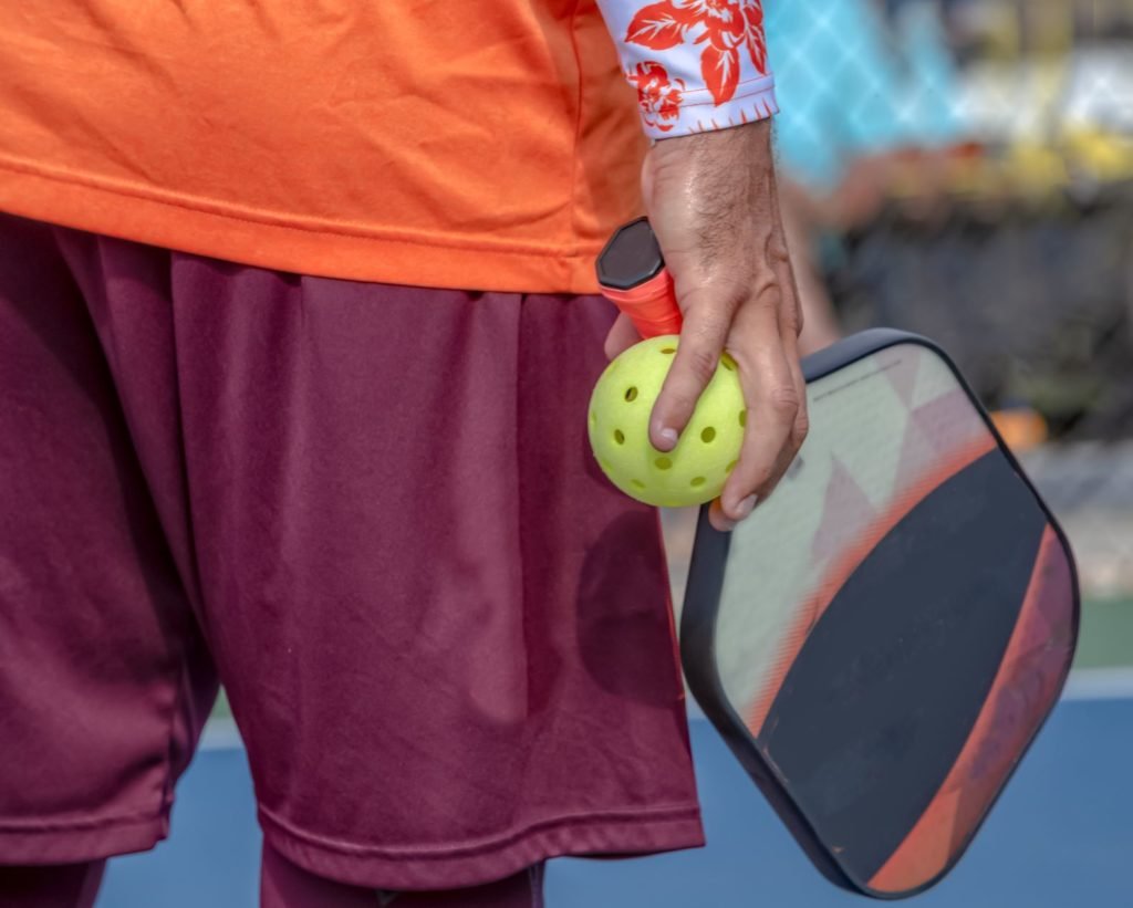Person holding pickleball and pickleball paddle grip