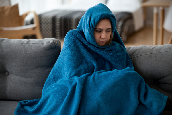 woman wrapped up in blanket from feeling cold
